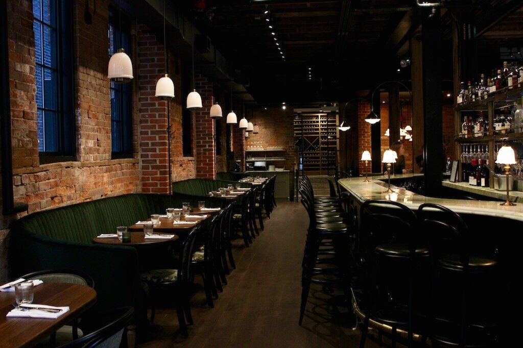 Lapinou dining room with green banquettes and exposed brick